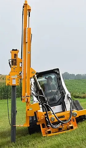 Rhino Solar Pro skid steer pile driver setting a solar pile on sloping ground